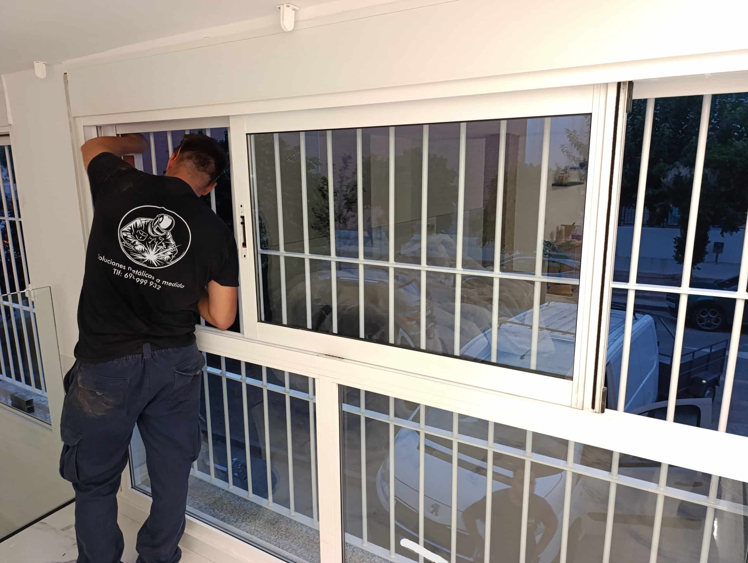 Profesional trabajando junto a un cerramiento acristalado con rejas blancas
