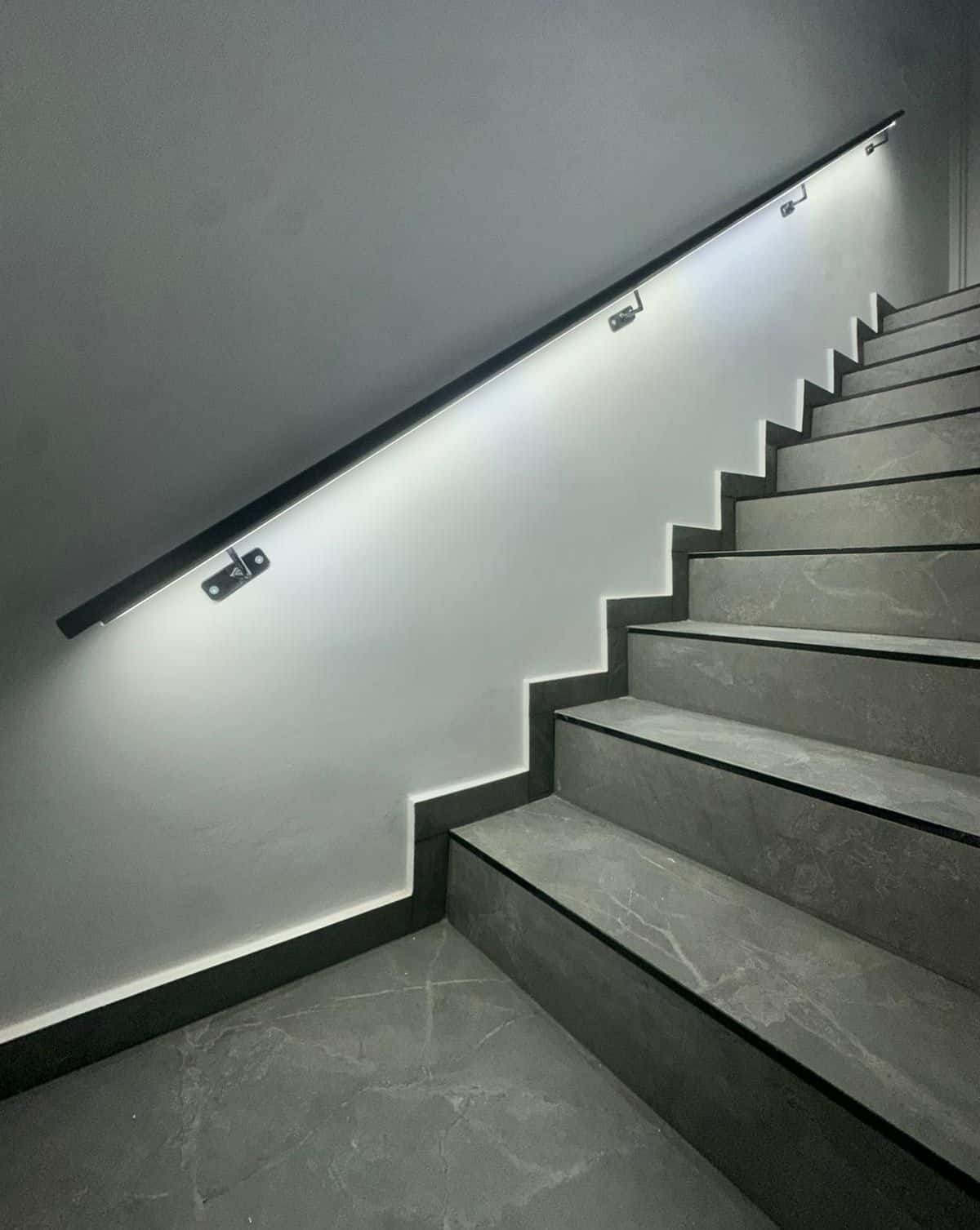 Pasamanos negro fijado a la pared junto a una escalera interior